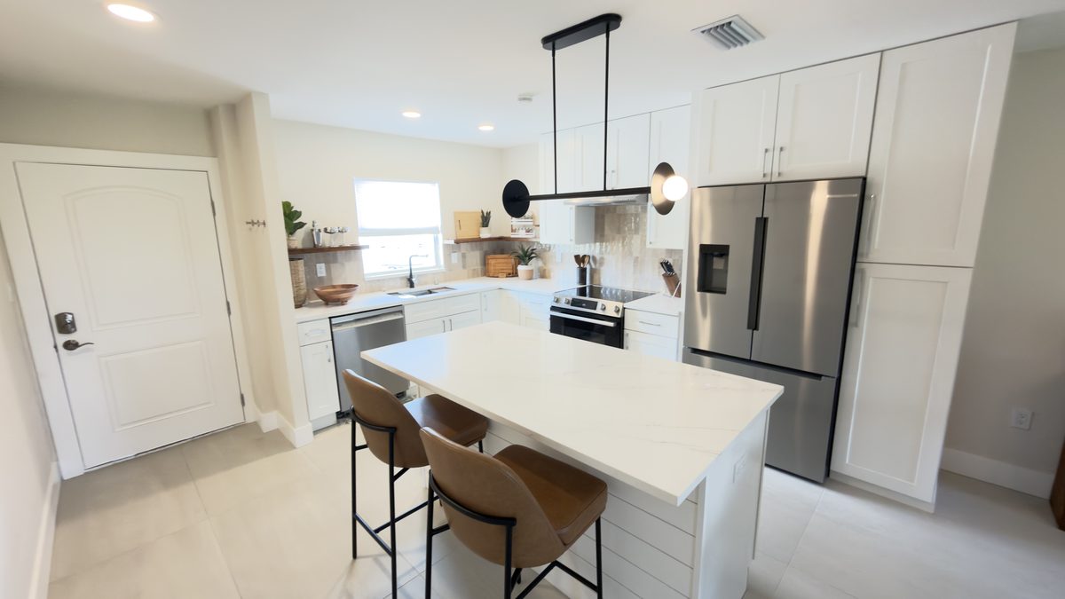 White kitchen remodel with quartz island and stainless appliances